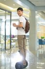 Sorridente jovem empresário com mochila segurando café para ir e andar de scooter de auto-equilíbrio no escritório — Fotografia de Stock