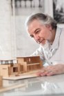 Professional focused mature architect working with building model at workplace — Stock Photo