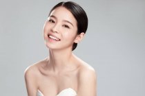 Portrait of beautiful happy young asian woman smiling at camera isolated on grey background — Stock Photo