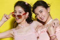 Красиві стильні молоді жінки позують разом і посміхаються на камеру на жовтому — стокове фото