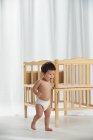Full length view of adorable excited asian toddler walking near crib — Stock Photo