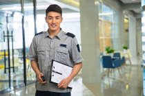 Улыбающийся молодой азиатский охранник держит рацию и планшет — стоковое фото