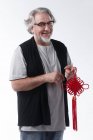 Homem de meia-idade segurando nó chinês vermelho e sorrindo para a câmera isolada em cinza — Fotografia de Stock