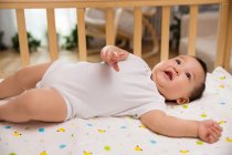 Adorable asian infant baby lying in crib and looking up — Stock Photo