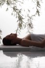Vista lateral da bela jovem mulher asiática com toalha no corpo deitado na mesa de massagem no spa — Fotografia de Stock