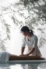 Обрезанный снимок массажистки, делающей массаж молодой женщине в спа — стоковое фото