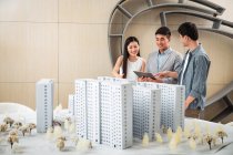 Усміхнені професійні молоді азіатські архітектори обговорюють проект в офісі — стокове фото