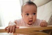 Primer plano vista de adorable asiático bebé con boca abierta sentado en mecedora en casa - foto de stock