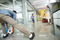 Молоді азіатські бізнесмени і бізнесмени грають у футбол разом в сучасному офісі — стокове фото
