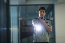 Joven asiático seguridad guardia holding walkie-talkie y linterna en la noche - foto de stock
