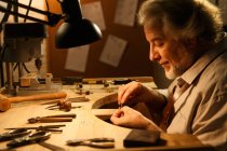 Vue de profil de concepteur de bijoux professionnel travaillant avec des outils et bague à l'atelier — Photo de stock