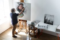 Aus der Vogelperspektive eines männlichen Künstlers, der Selbstporträt im Atelier malt — Stockfoto