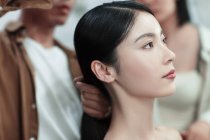 Cortado tiro de estilistas fazendo penteado para bela jovem mulher asiática no salão de beleza — Fotografia de Stock