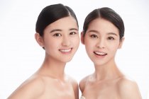 Красиві щасливі молоді азіатські жінки посміхаються на камеру ізольовані на білому — стокове фото