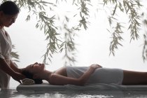 Вид сбоку на молодую азиатку, получающую массаж головы в спа — стоковое фото