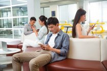 Молоді Азіатські люди сидять і використовують смартфони в сучасному офісі — стокове фото