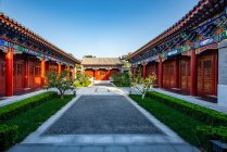 Красива традиційна азіатська архітектура з червоними колонами і зеленими рослинами у дворі — стокове фото