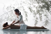 Vue latérale de masseuse faisant massage du corps à la jeune femme dans le spa — Photo de stock