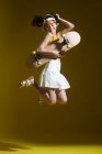 Full length view of beautiful happy asian girl holding skate and jumping in studio — Fotografia de Stock