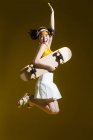 Приваблива щаслива азіатська дівчина в прозорій шапці тримає скейтборд і стрибає в студії — стокове фото
