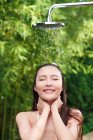 Vue de face de belle sourire asiatique fille prendre douche avec les yeux fermés — Photo de stock