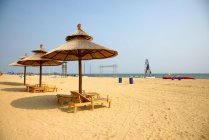 Parasols et chaises longues sur la plage de sable fin en mer — Photo de stock