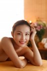 Beautiful happy naked asian girl lying and smiling at camera in spa — Stock Photo