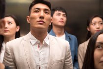 Young asian businessmen and businesswomen standing together in elevator — Stock Photo