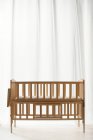 Cama de madeira marrom do bebê no interior vazio da sala de luz — Fotografia de Stock