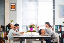 Side view of tired young coworkers yawning and sleeping at desk in office — Stock Photo