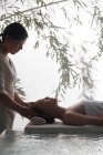 Vue latérale de jeune femme asiatique détendue recevant un massage de la tête dans un spa — Photo de stock