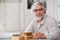 Professional mature architect in eyeglasses working with project and looking at camera in office — Stock Photo