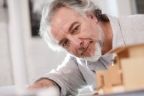Professional mature architect working with building model at workplace, selective focus — Stock Photo