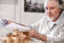 Professional mature architect working with blueprint and building project in office — Stock Photo