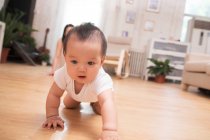 Adorable asian baby crawling on floor while mother sitting behind at home — Stock Photo