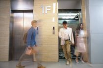 Jóvenes empresarios borrosas caminando cerca del ascensor en la oficina - foto de stock