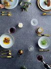 Вид зверху на людей, які проводять романтичну вечерю з вином, смачні страви та свічки на сірому, обрізаному дробі — стокове фото