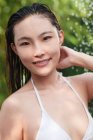 Красивая молодая азиатка в бикини принимает душ и улыбается в камеру — стоковое фото