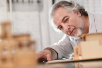Professional mature architect working with building model at workplace, selective focus — Stock Photo