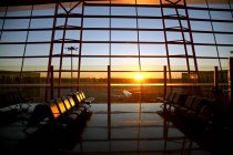 Vista de aviões através da janela do lounge do aeroporto vazio durante o pôr do sol — Fotografia de Stock