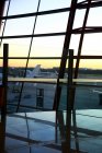 Vue des avions par la fenêtre depuis le salon vide de l'aéroport pendant le coucher du soleil — Photo de stock