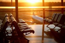 Plane view through window from empty airport lounge during sunset — Stock Photo