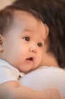 Обрезанный снимок родителя, несущего очаровательного азиатского младенца дома — стоковое фото