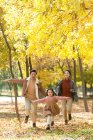 Happy asian parents and daughter running in autumnal park — Stock Photo