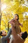 Feliz asiático pais levantando filha no outonal parque — Fotografia de Stock