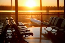 Plane view through window from empty airport lounge during sunset — Stock Photo