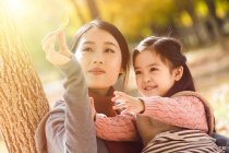 Счастливая азиатская мать и дочь глядя на осенний лист в парке — стоковое фото
