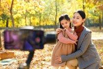 Glücklicher asiatischer Vater fotografiert Tochter und Ehefrau mit Smartphone im herbstlichen Park — Stockfoto