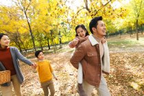 Feliz joven asiático familia con dos niños caminando juntos en otoño parque - foto de stock