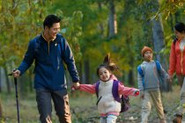 Feliz joven asiático familia con mochilas senderismo juntos en bosque - foto de stock
